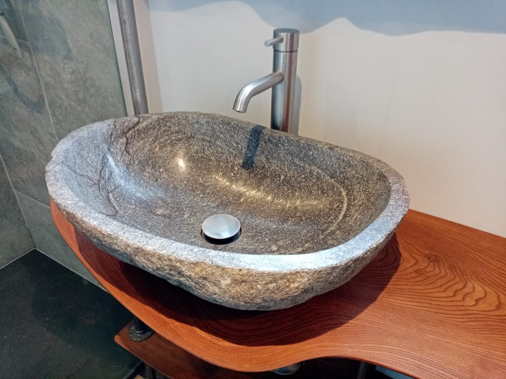 Boulder stone bathroom basin on elm wood slab designed by Paint and Plan